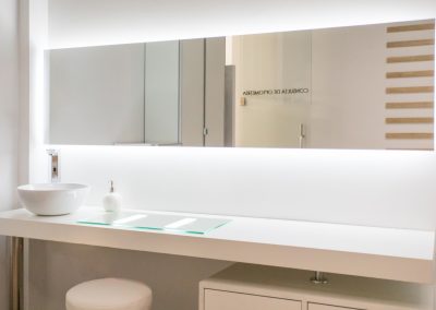 Lentillero con mesa y espejo espejo en pared, con almacenamiento inferior, ideal para ópticas, mobiliario comercial diseñado por Estudio AMA